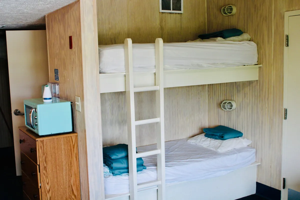 This image focuses on a set of bunk beds with a ladder, next to a dresser and a playful blue microwave. The arrangement provides extra sleeping options, making the space friendly for larger groups or families. The youthful, casual vibe suggests the studio's flexibility in accommodating various guests and activities.