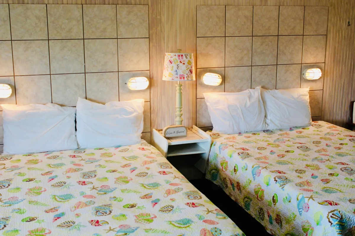 This image shows a comfortable interior bedroom setting with colorful bedspreads, a unique lamp, and wall decor. The soft textures and inviting atmosphere suggest a cozy place to unwind after a day spent exploring outdoors.